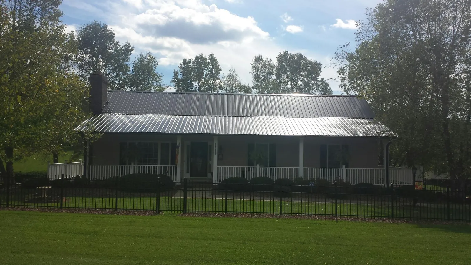 Gray metal roof on a brick ranch with a full width front porch — Gutter Guard Installation work by our crew in Hammond